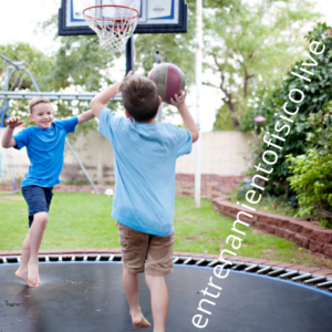 niños jugando basket sobre un trampolin